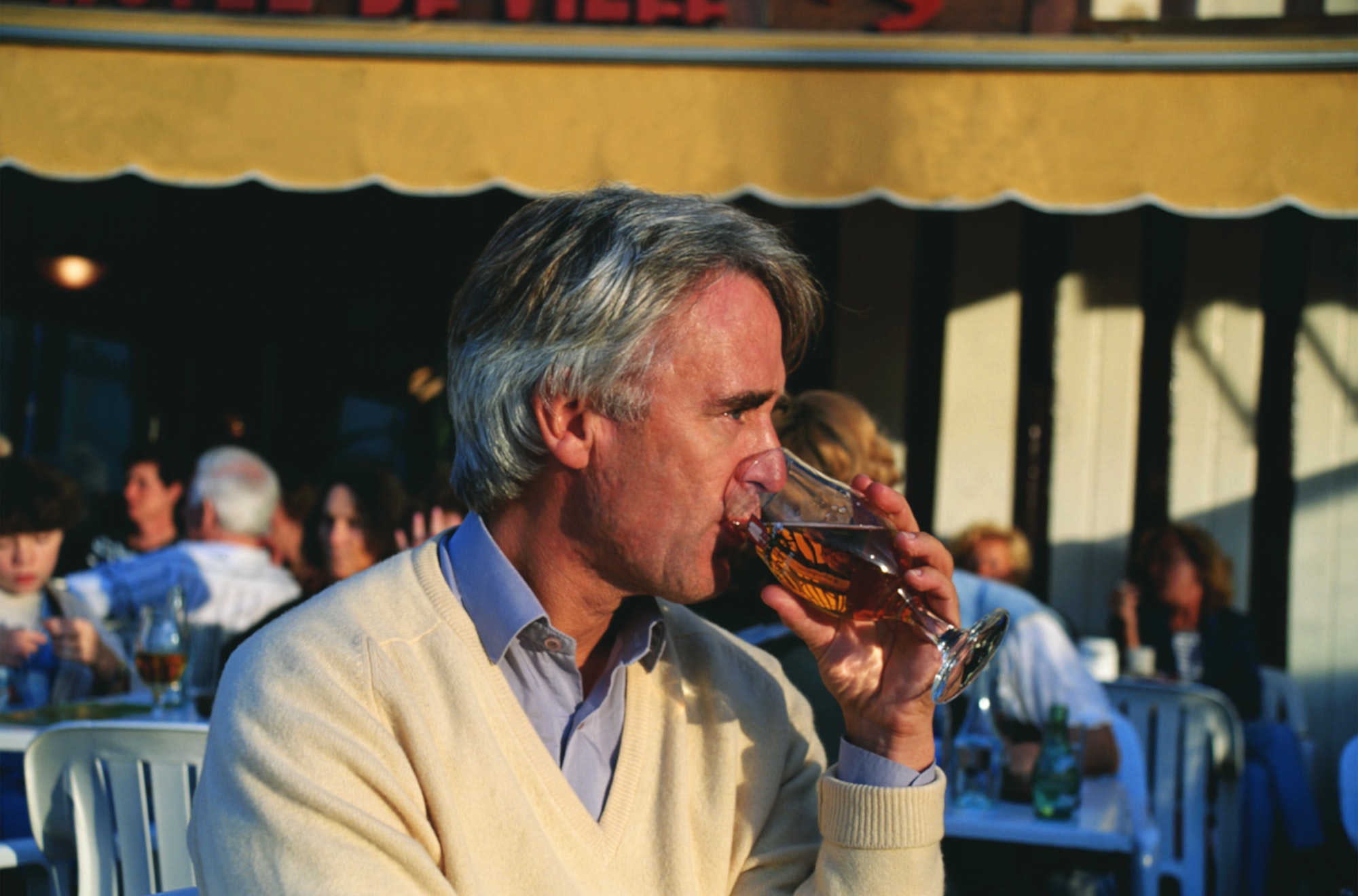 Man enjoying a beer in the early evening at a harbour side cafe in Honfleur, Normandy, France