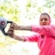 A pretty woman in a pink outfit doing exercise with a weight on a sunny day