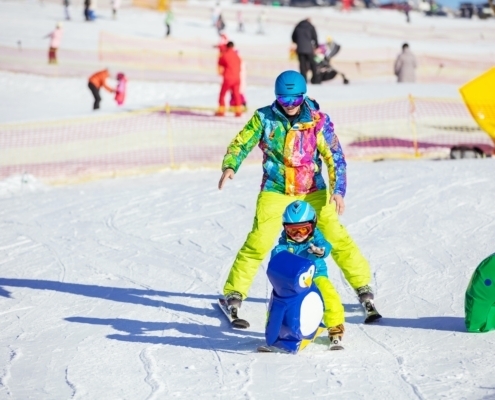 Father teaching little son to ski in children's area