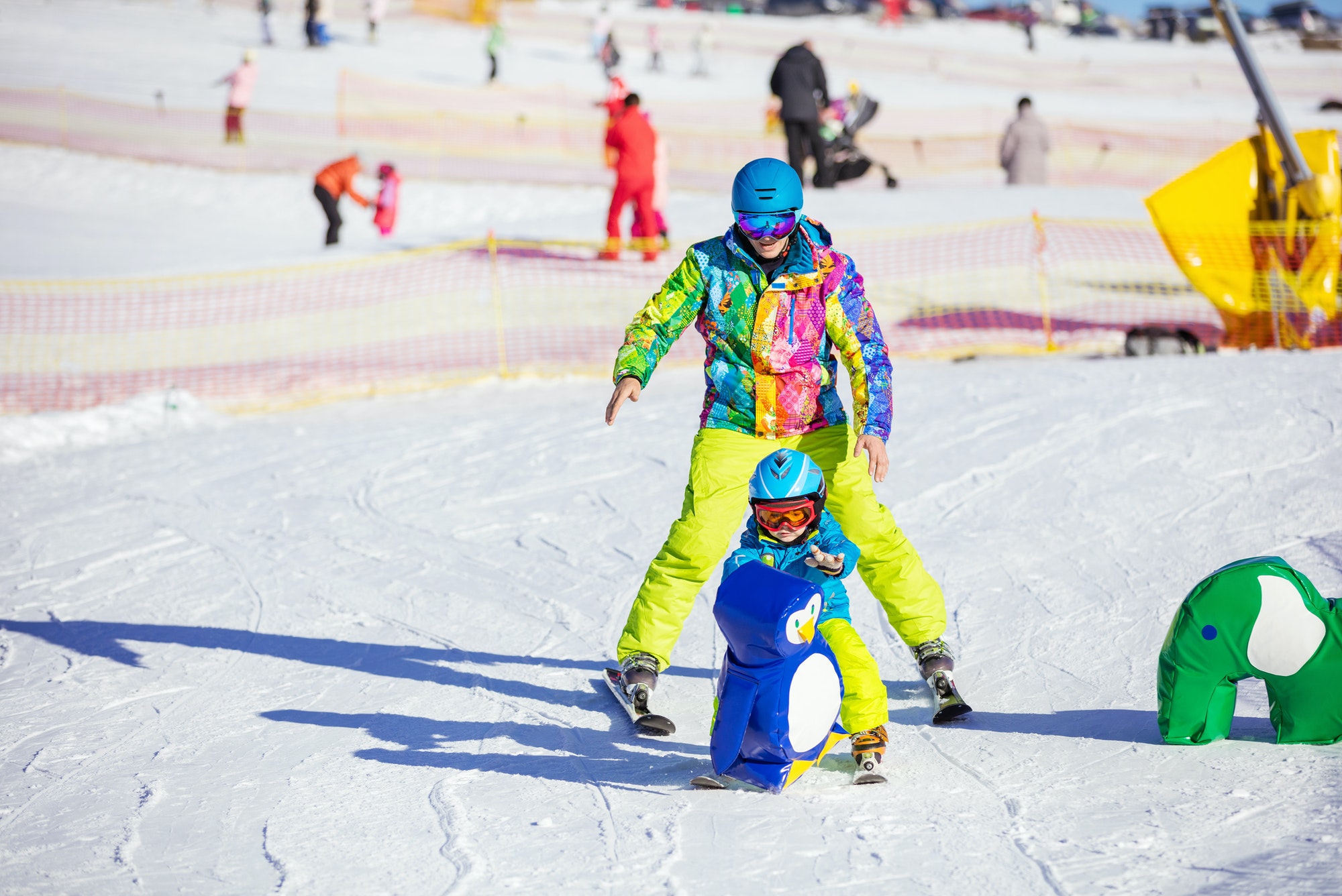 Father teaching little son to ski in children's area