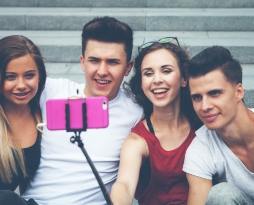 Group of friends with mobile phone on selfie stick and taking picture