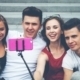 Group of friends with mobile phone on selfie stick and taking picture