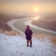 Young child watches the sun go down in winter